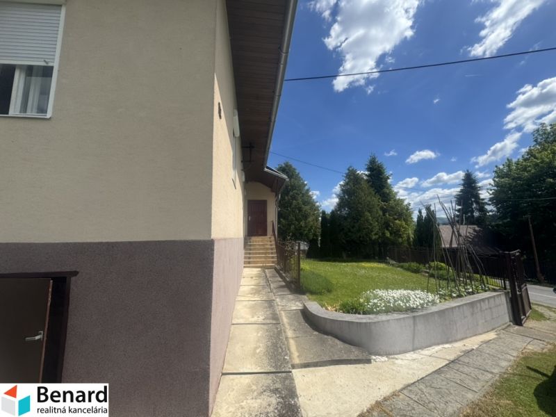 Ein Einfamilienhaus in Orlové mit einem Gehweg und Grünflächen, umgeben von Bäumen und blauem Himmel.