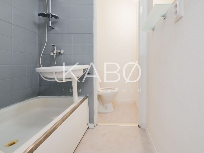 Badezimmer in einem Einzimmerapartment mit Dusche und Toilette, einfaches Design.