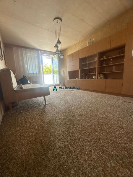 Wohnzimmer in einer Zweizimmerwohnung mit offenen Balkontüren und Retro-Möbeln.