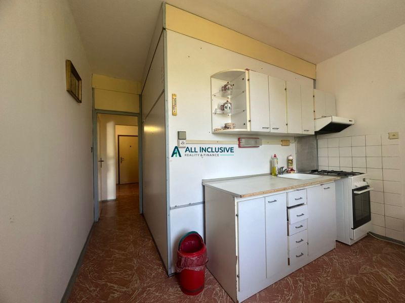 Küchenecke mit weißen Schränken und Herd in einer 2-Zimmer-Wohnung.