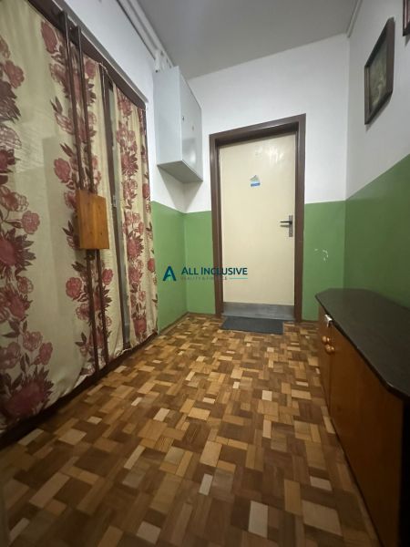 Flur einer 2-Zimmer-Wohnung mit Holzboden und Blumenvorhängen.