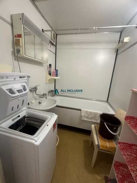 Badezimmer mit Waschmaschine und Badewanne in einer 2-Zimmer-Wohnung mit Holzdekor.