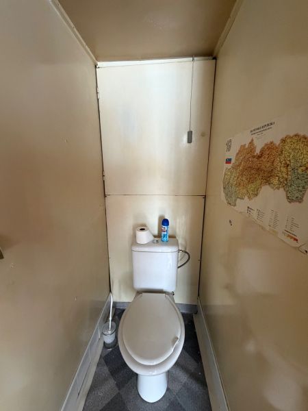 Eine enge Toilette mit einer Karte an der Wand in einer 3-Zimmer-Wohnung.