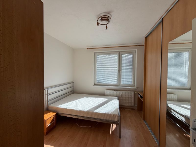 Schlafzimmer in einer 3-Zimmer-Wohnung mit Bett und Einbauschrank, Boden mit Holzdekor.