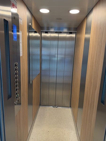 Ein Aufzug mit einem Boden in Holzoptik und Wänden aus Metall.