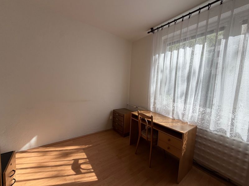 Ein Zimmer mit einem Schreibtisch und einem Stuhl, ein Boden mit Holzdekor.
