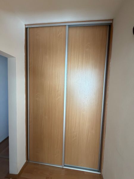 Ein Schrank mit Schiebetüren und einem Boden mit Holzdekor in einer 3-Zimmer-Wohnung.