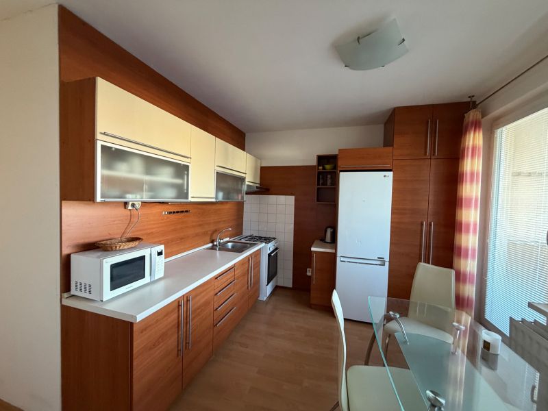 Küche in einer 3-Zimmer-Wohnung mit weißer Küchenzeile und Boden in Holzoptik.