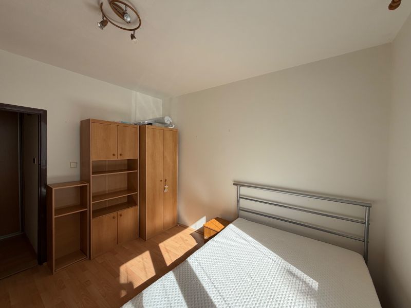 Schlafzimmer in einer 3-Zimmer-Wohnung mit weißen Wänden und einem Boden in Holzoptik.