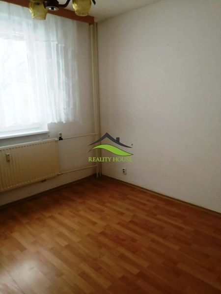 Ein Zimmer in einer 3-Zimmer-Wohnung mit einem Boden in Holzoptik, einem Vorhang und einem Heizkörper.