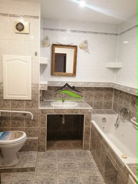 Badezimmer in einer 3-Zimmer-Wohnung mit Badewanne, Spiegel und Toilette, gefliest.
