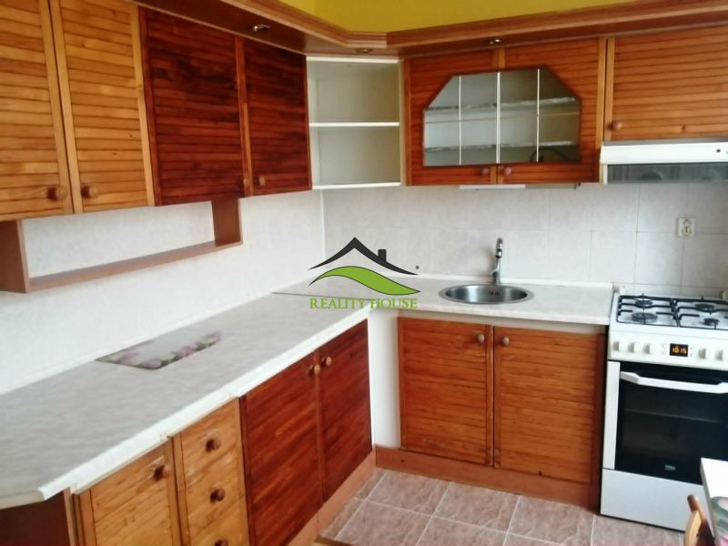 Küche in einer 3-Zimmer-Wohnung mit Holzschränken und weißer Arbeitsplatte.
