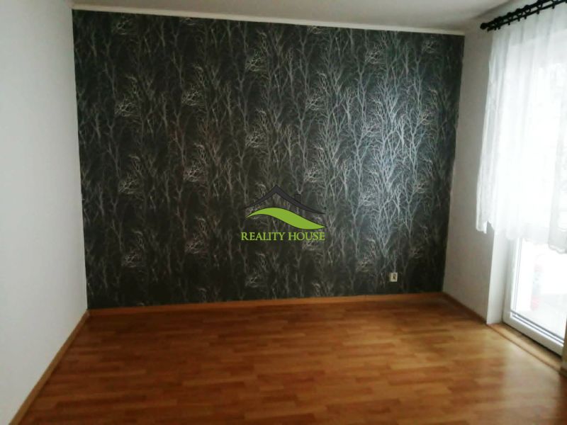 Ein Zimmer in einer 3-Zimmer-Wohnung mit einem Holzboden und gemusterten Tapeten.
