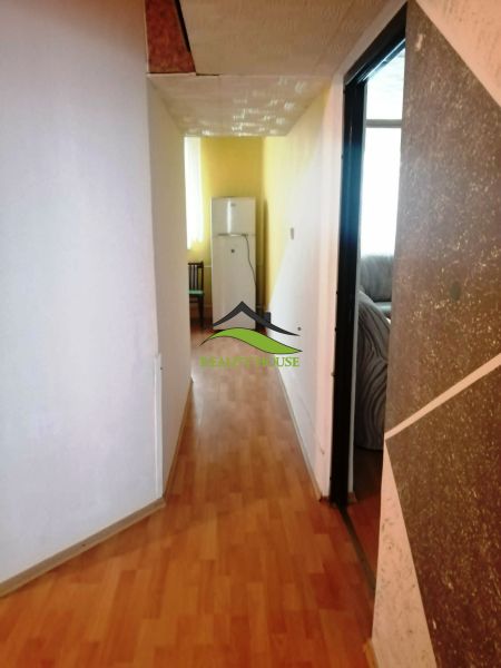 Der Flur in der 3-Zimmer-Wohnung mit einem Boden in Holzoptik, der zum Kühlschrank führt.