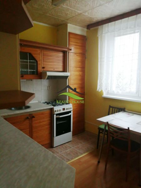 Küche in einer 3-Zimmer-Wohnung mit Holzboden, Esstisch und Herd.