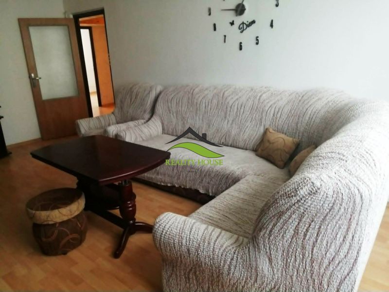 Wohnzimmer in einer 3-Zimmer-Wohnung mit einer Eckcouch und einem Boden in Holzoptik.