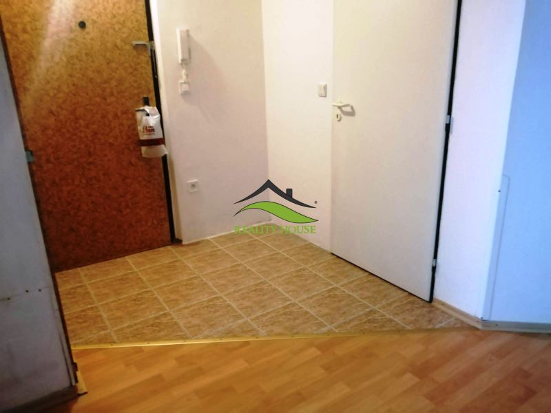 Flur einer 3-Zimmer-Wohnung mit Fliesen und Bodenbelag in Holzoptik.