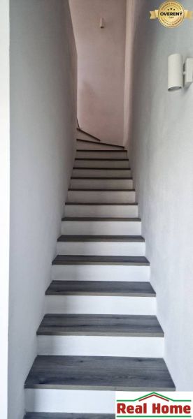 Eine Treppe mit einem Boden in Holzoptik, die in einem Einfamilienhaus nach oben führt.
