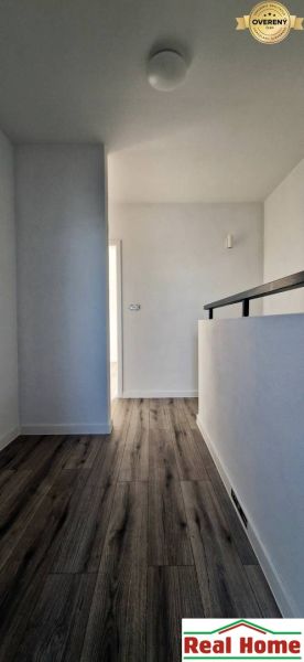 Ein Flur in einem Einfamilienhaus mit einem Boden in Holzoptik und weißen Wänden.