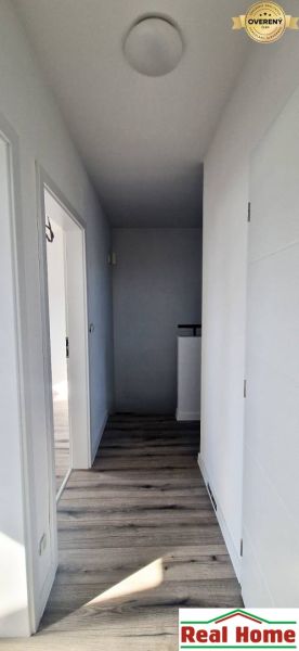 Ein Flur in einem Einfamilienhaus mit weißen Wänden und einem Boden in Holzoptik.