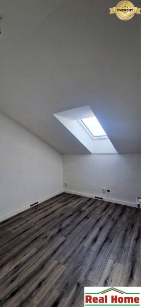 Dachzimmer mit Holzboden und Dachfenster in einem Einfamilienhaus.