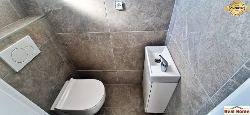 Toilette mit Waschbecken im Einfamilienhaus, graue Wandfliesen.