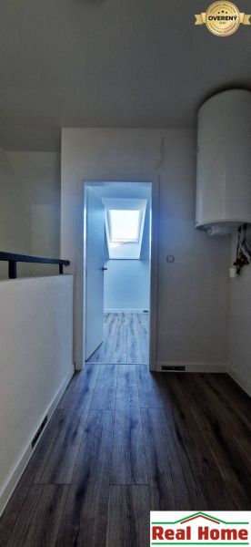 Flur in einem Einfamilienhaus mit Holzboden, im Hintergrund ein Dachfenster.