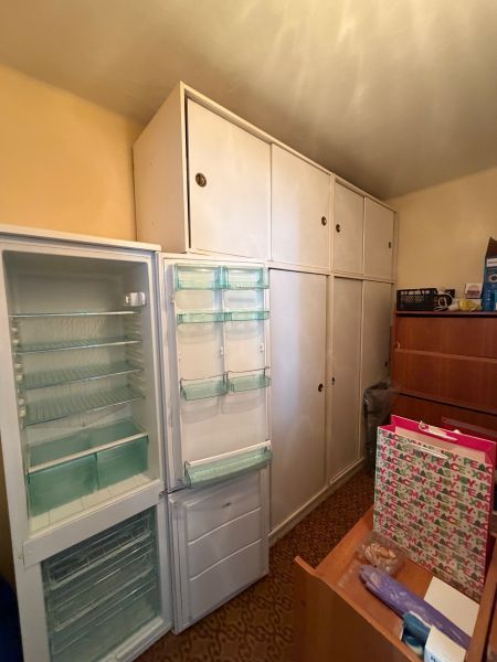 Geöffneter Kühlschrank und Einbauschränke im Zimmer einer 2-Zimmer-Wohnung.