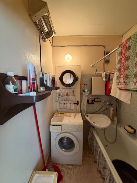 Badezimmer in einer 2-Zimmer-Wohnung mit Dusche, Waschbecken und Waschmaschine.