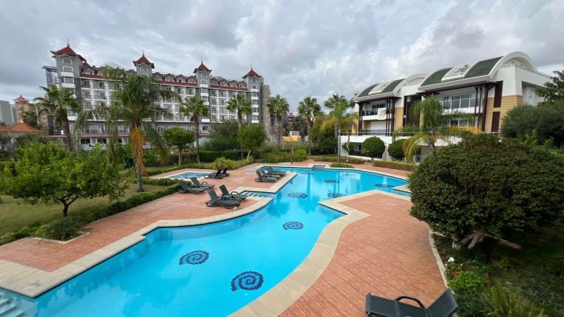 Hotelpool mit Palmen und Gebäuden im Ferienort Side, Türkei, für Besondere Immobilien.