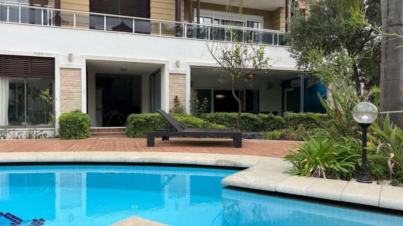 Ein Pool mit Liege und Garten vor einer besonderen Immobilie in Side, Türkei.