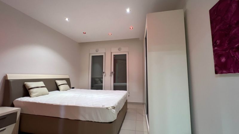 Schlafzimmer mit Doppelbett, weißen Wänden und Schrank, Besondere Immobilien.