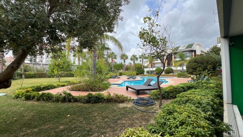 Ein von Grün und Liegestühlen umgebener Pool im Garten in Side, Türkei, für besondere Immobilien.