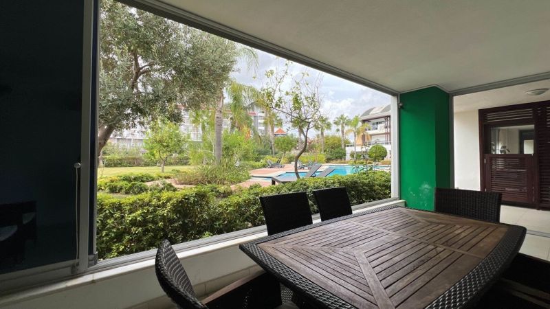 Überdachte Terrasse mit Gartenmöbeln und Blick auf den Pool in Side, Türkei.