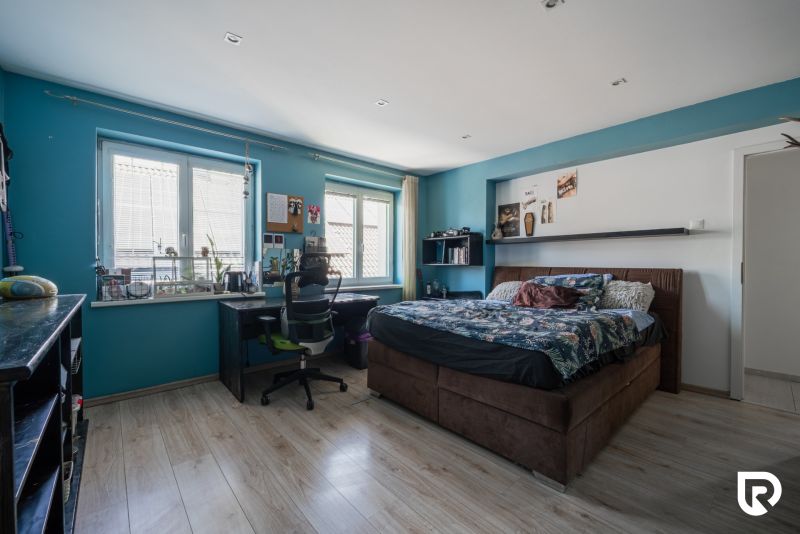 Schlafzimmer in einem Einfamilienhaus, blaue Wände, Bett, Schreibtisch und Boden mit Holzdekor.