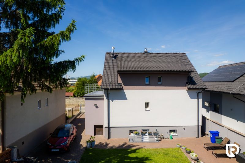 Ein Einfamilienhaus in der Jahodová-Straße in Trenčín mit Hof, Auto und Grünflächen.
