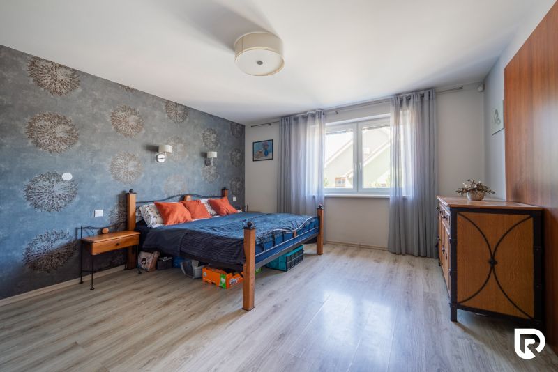 Schlafzimmer in einem Einfamilienhaus mit Holzboden, Tapete und massiven Möbeln.