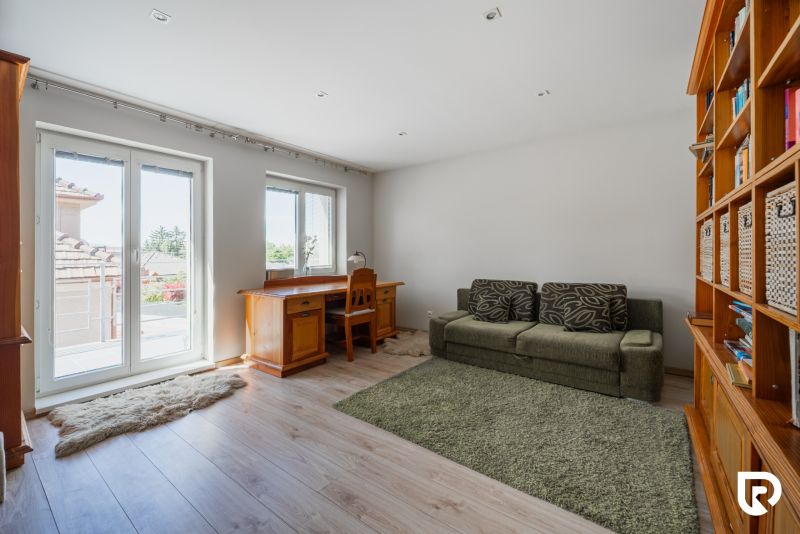 Wohnzimmer in einem Einfamilienhaus mit Holzboden, Sofa und Schreibtisch.