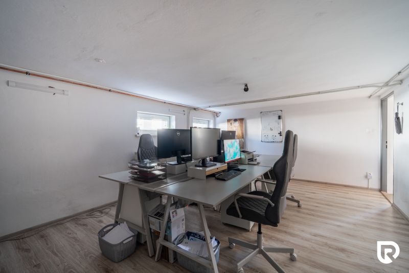 Ein Büroraum in einem Einfamilienhaus mit einem Boden in Holzoptik und Schreibtischen.