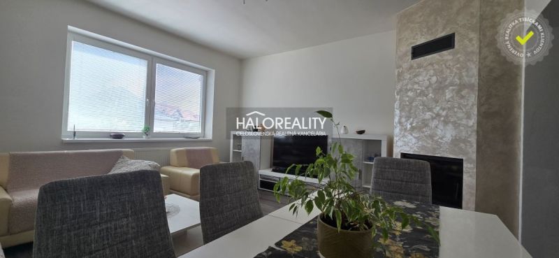 Wohnzimmer in einem Einfamilienhaus mit Kamin, Fernseher, Sitzgarnitur und Fenster mit Jalousien.