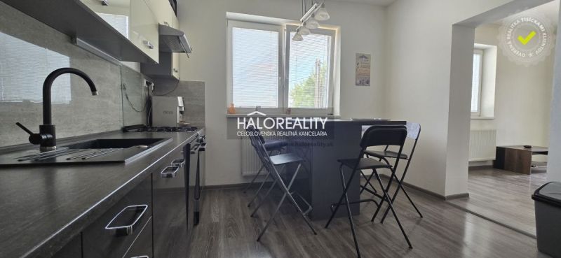 Küche in einem Einfamilienhaus mit Klappstühlen und einem Boden in Holzoptik.