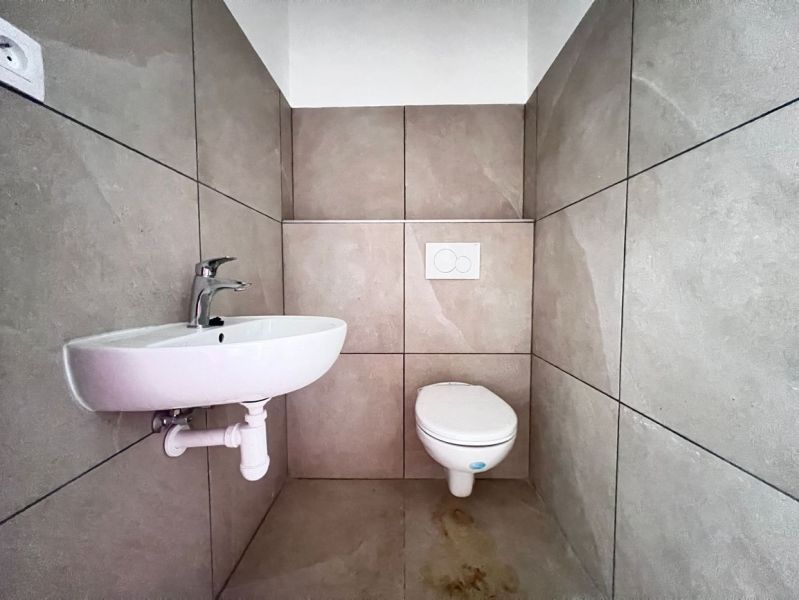 Toilette mit Waschbecken, neutrale Fliesen, Geschäftsräume.