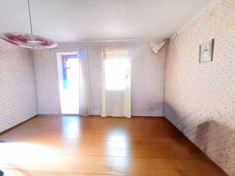 Ein Zimmer in einem Einfamilienhaus mit einem Holzboden, einem Blumenleuchter und einem Bild an der Wand.