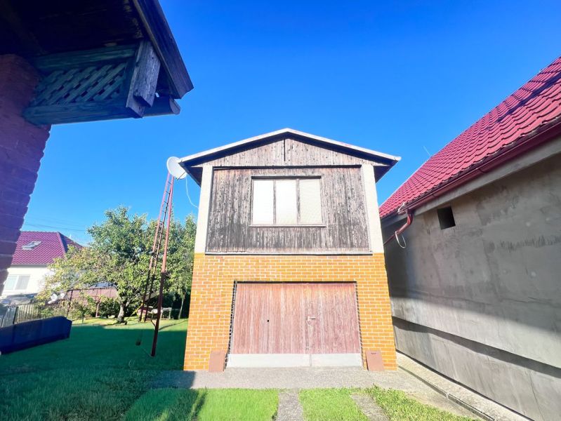 Ein Einfamilienhaus in Žirany mit einer Ziegelgarage und Holzelementen im Garten.