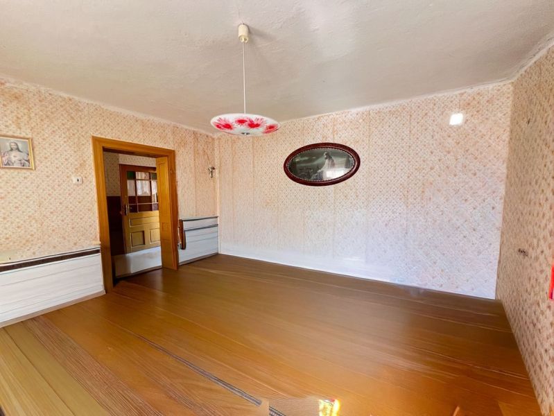 Ein Zimmer in einem Einfamilienhaus mit einem Holzboden und gemusterten Wänden.