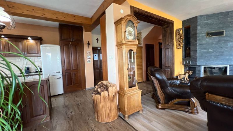 Innenraum der Villa mit Holzboden, antiker Uhr und Kamin.