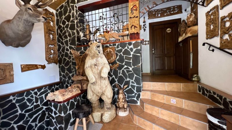 Interieur der Villa mit hölzernen Tierskulpturen und Steinwänden.