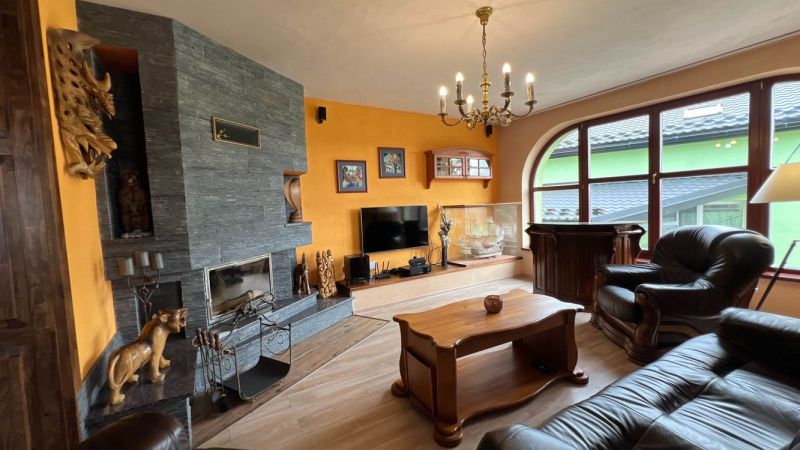 Wohnzimmer in einer Villa mit Kamin, Holzboden und Ledermöbeln.