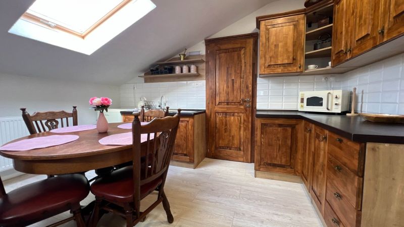Küche in der Villa mit Holzschränken, Esstisch und Boden mit Holzdekor.