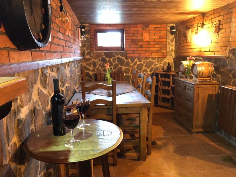 Weinkeller mit Backsteinwänden und Holztisch in einer Villa, Wein auf dem Tisch.